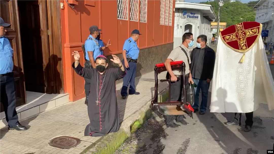 Monseñor Rolando José Álvarez reza frente a agentes policiales, quienes se han mantenido alrededor de la casa cural donde permanece. Cortesía
