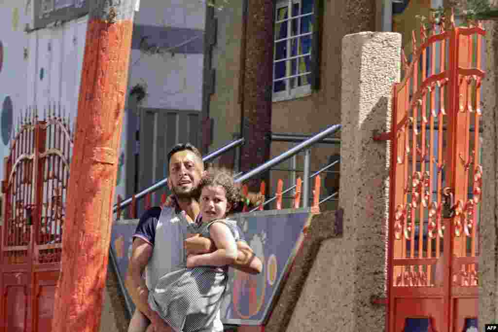 A Palestinian man carries his daughter after evacuating his home during an Israeli air strike in Gaza City. Israel bombarded Islamic Jihad positions in the Gaza Strip for a third day as violence escalated, with 31 Palestinians killed and militants firing their first rockets at Jerusalem.