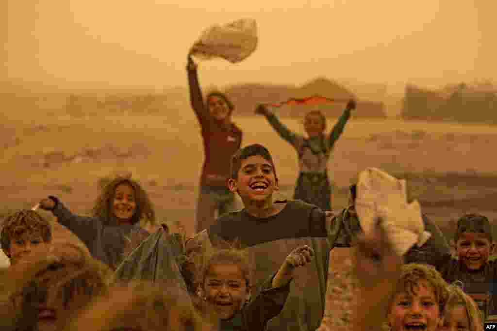 Children play amid a sandstorm at the Sahlah al-Banat camp for displaced people in the countryside of Raqa in northern Syria, Oct. 17, 2022.