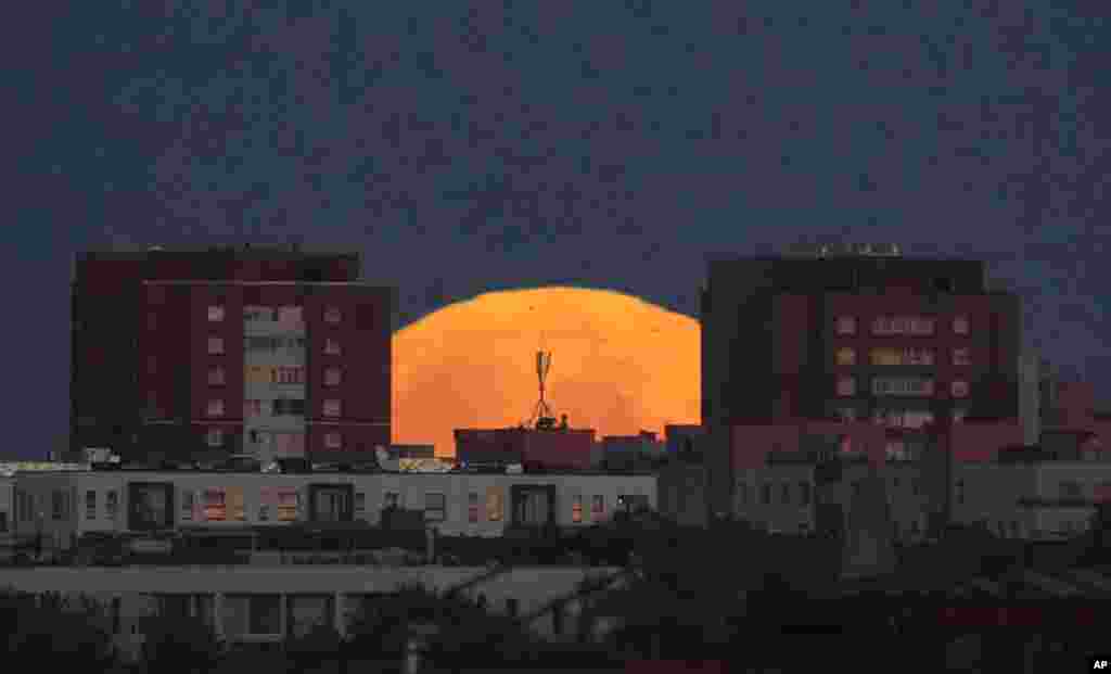 A full moon is seen behind buildings in downtown Tallinn, Estonia.