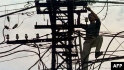 Một người thợ đang mắc dây điện trên một con đường ở Hà Nội