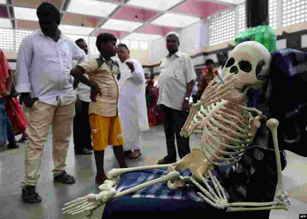 Bystanders look a replica of a human skeleton smoking a cigarette during an awareness rally marking 'World No-Tobacco Day,' in Chennai, India.