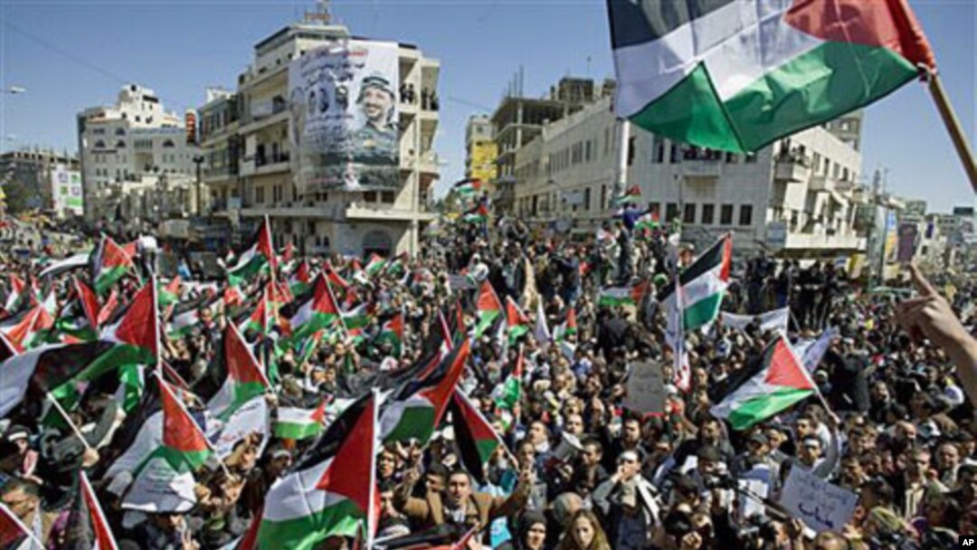 Palestinians wave flags and chant slogans during a rally calling for a reconciliation between the rival Palestinian leading factions Hamas in Gaza and Fatah in the West Bank, in the West Bank city of Ramallah, March 15, 2011