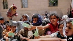 FILE - Yemenis present documents in order to receive food rations provided by a local charity, in Sanaa, Yemen. The U.N.'s humanitarian chief warned a day earlier that unless the Saudi-led coalition lifts its blockade, Yemen will face "the largest famine the world has seen for many decades, with millions of victims."