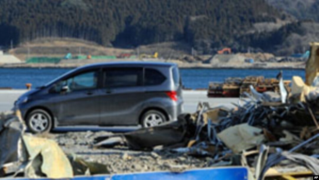 A car passes in front of tsunami debris piled up on the wharf in Ofunato, Iwate Prefecture nearly one year after the March 11 tsunami devastated the area, January 15, 2012.