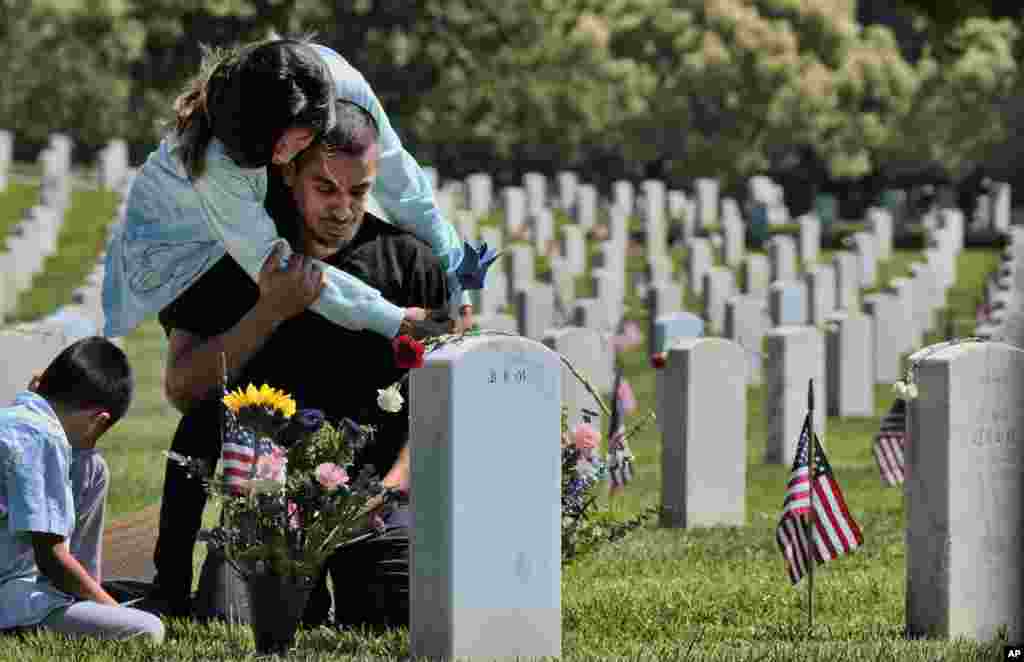 Carla Martinez comforts her cousin Ceaser Martinez as he weeps over his brother's grave on Memorial Day at the Veterans National Cemetery in Los Angeles. Rodrigo Matinez was killed in action in Iraq in 2004.