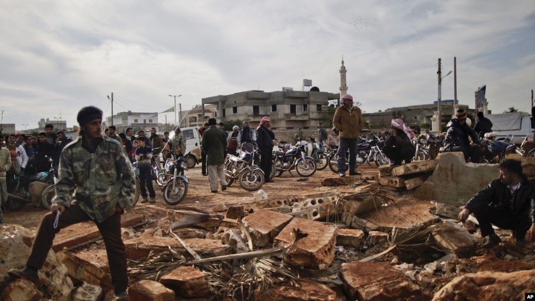 Syrians wait alongside rubble in Maaret Misreen near Idlib to buy bread at a local bakery, December 12. (AP)