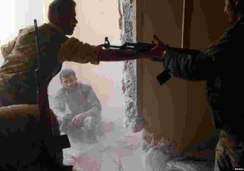 A Free Syrian Army fighter passes an AK-47 rifle to his fellow fighter in Aleppo, August 14, 2012.
