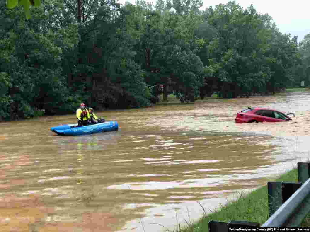 Crew of a water rescue vessel is seen near a car in flood waters on Clara Barton Parkway near Washington, D.C., July 8, 2019 in this picture obtained from social media.
