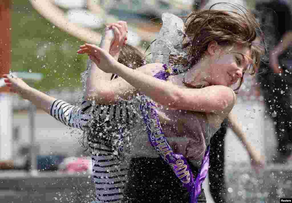 Secondary school graduates play in a fountain as they celebrate the last day of school, traditionally called the 'last bell' in central Kyiv, Ukraine.