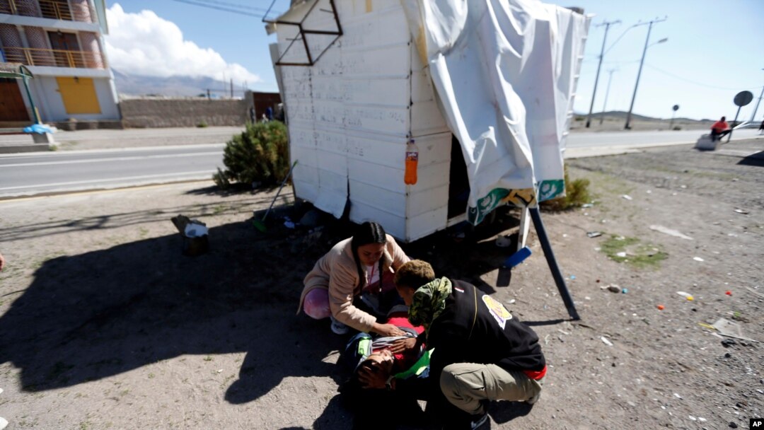 Unos migrantes venezolanos atienden a un compañero, cerca de Colchane, Chile, el 6 de febrero de 2021.