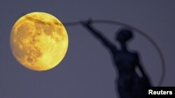 A statue is seen silhouetted against a supermoon in Brussels, Belgium, Sept. 26, 2015. REUTERS/Yves Herman.