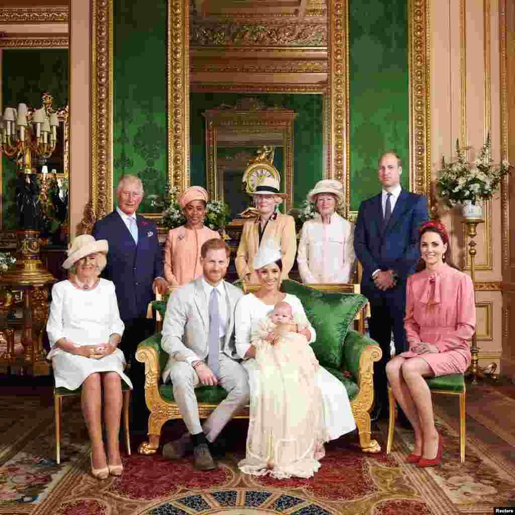 This official photograph released by the Duke and Duchess of Sussex shows Britain's Prince Harry, Duke of Sussex (centre left), and his wife Meghan, Duchess of Sussex holding their baby son, Archie Harrison Mountbatten-Windsor flanked by (L-R) Britain's Camilla, Duchess of Cornwall, Britain's Prince Charles, Prince of Wales, Ms Doria Ragland, Lady Jane Fellowes, Lady Sarah McCorquodale, Britain's Prince William, Duke of Cambridge, and Britain's Catherine, Duchess of Cambridge in the Green Drawing Room at Windsor Castle, west of London, July 6, 2019.