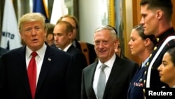 FILE - Secretary of Defense James Mattis, right, escorts U.S. President Donald Trump as he greets military personnel at the Pentagon, July 20, 2017. 