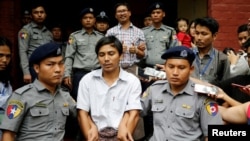 FILE - Detained Reuters journalist Kyaw Soe Oo and Wa Lone are escorted by police as they leave after a court hearing in Yangon, Myanmar, Aug. 20, 2018.
