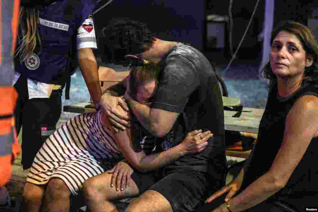 People react at the site where a rocket launched from the Gaza Strip landed in Tel Aviv, Israel, Oct. 7, 2023.