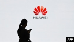 (FILES) This file photo taken on March 6, 2019 shows a staff member of Huawei using her mobile phone at the Huawei Digital Transformation Showcase in Shenzhen, China's Guangdong province.