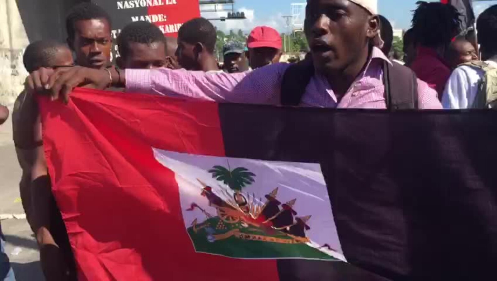 Manifestantes en el la vía del aeropuerto levantan la bandera roja y negra, un gesto desafiante, ya que es un símbolo de la dictadura-la bandera acutal de Haiti de roja y azul desde 1986-