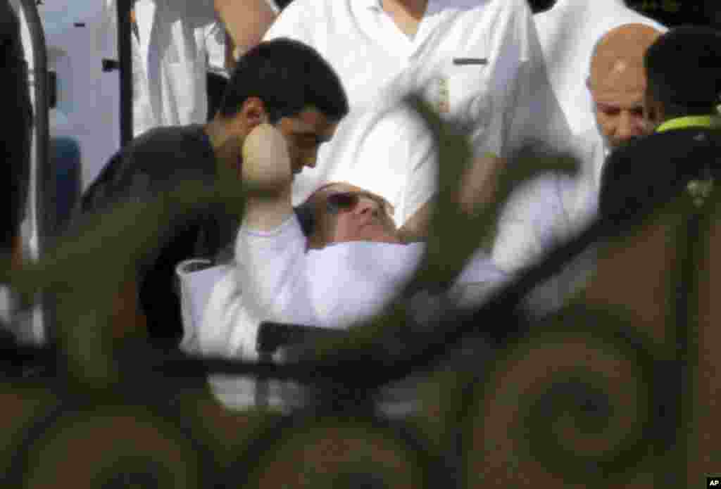 Egyptian medics escort former Egyptian President Hosni Mubarak into an ambulance after he was flown by a helicopter to the Maadi Military Hospital from Torah prison, Cairo, August 22, 2013.