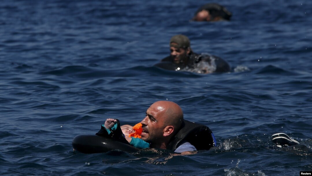 Un refugiado sirio sostiene a su bebé en un salvavidas, mientras nada hacia la costa frente a las isla de Lesbos, en Grecia.