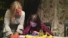 A year after the Women’s March, Katie Filipczyk Howard and her daughter Hannah look back on Facebook photos from that day and reminisce. (C. Presutti/VOA)