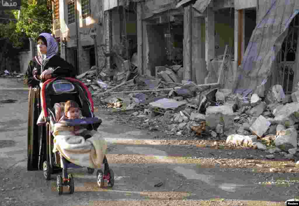 A woman stands along a damaged street in the besieged area of Homs, Syria, Jan. 29, 2014. 