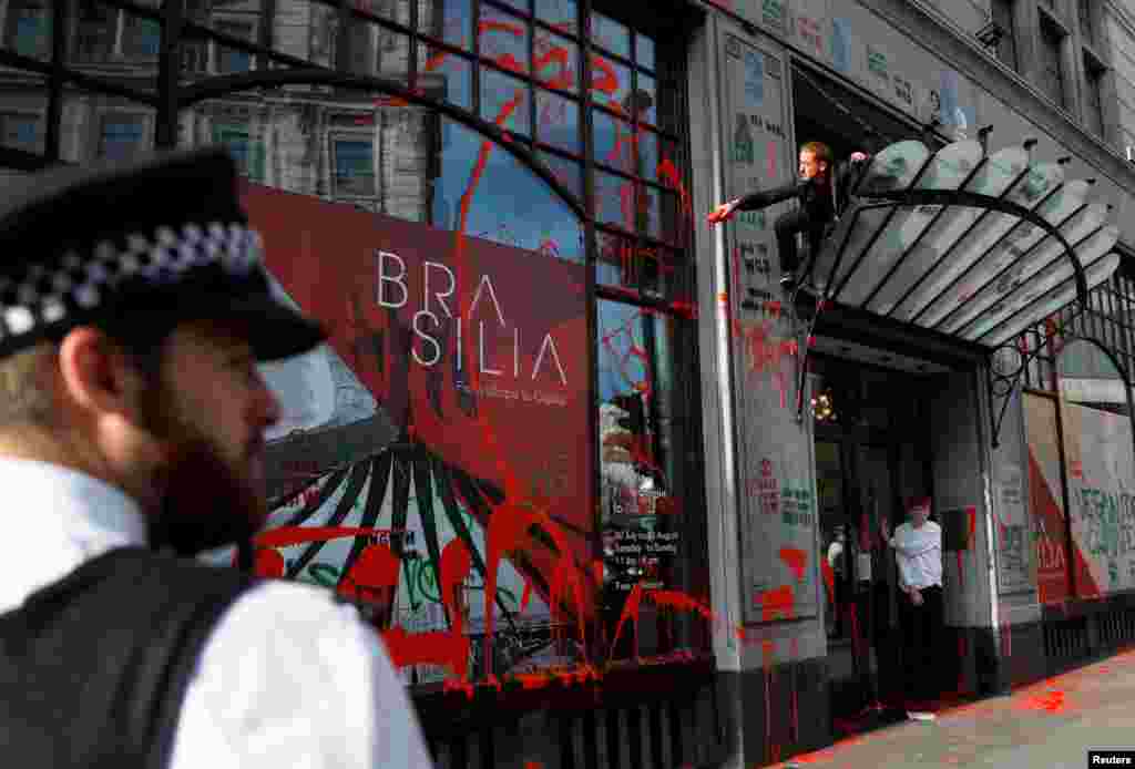 An activist splashes red paint over the facade of Brazilian Embassy in London during Extinction Rebellion climate change protest.