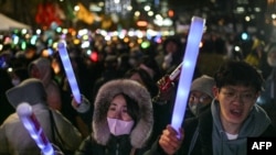 Pessoas participam num protesto que apela à destituição do Presidente da Coreia do Sul, Yoon Suk Yeol, em frente à Assembleia Nacional, em Seul, a 7 de dezembro de 2024.