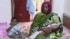 FILE - Meriam Ibrahim, sitting next to Martin, her 18-month-old son, holds the newborn daughter she gave birth to in jail in May at a prison in Khartoum, Sudan. 