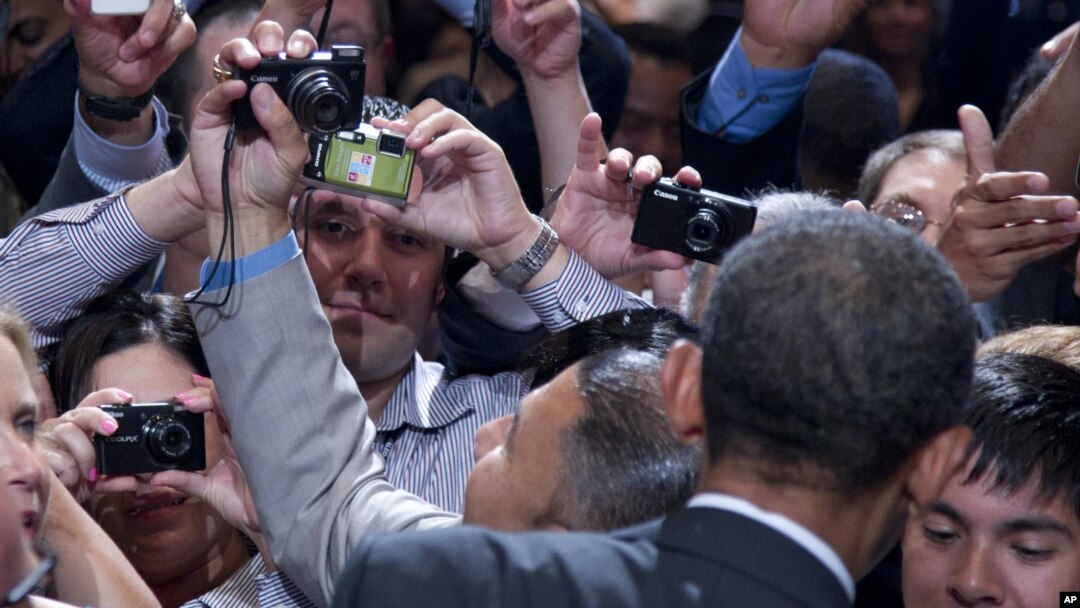 Members of the audience take photographs as President Barack Obama shakes hands at The National Association of Latino Elected and Appointed Officials’ Annual Conference at the Walt Disney World Resort in Florida, June 22, 2012.