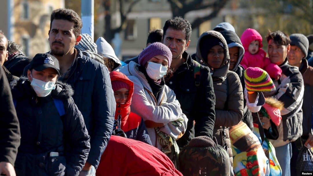 FILE - Migrants queue on a bridge crossing the border river Inn at the German-Austrian frontier between Braunau and Simbach am Inn near Passau, Germany, Nov. 1, 2015. 