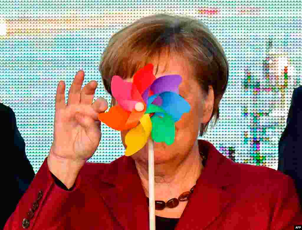 German Chancellor Angela Merkel is partly hidden by a toy wind wheel as she poses with children during the opening ceremony of the Arkona wind park in Sassnitz, northern Germany.