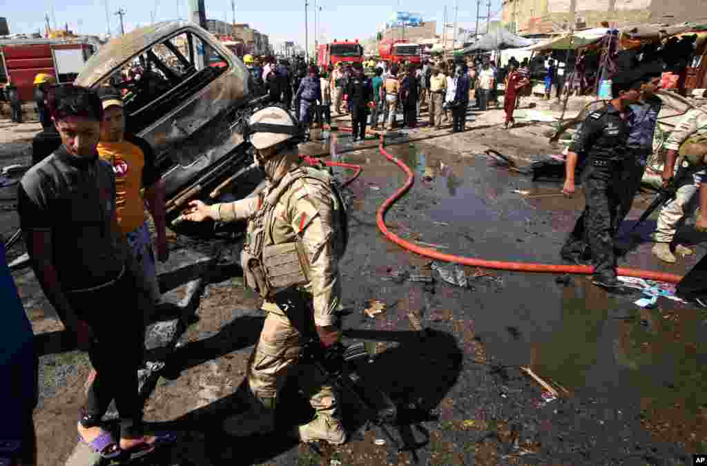 People and security forces inspect the site of a car bomb explosion in Basra, Iraq, July 29, 2013. 