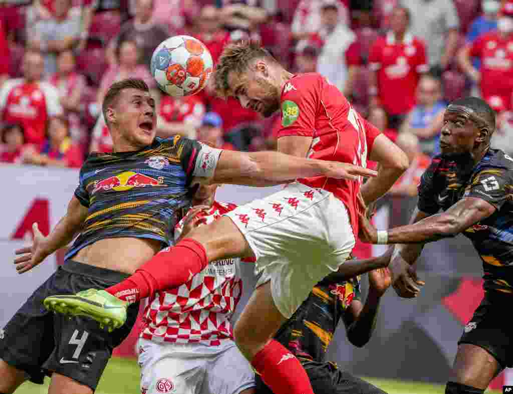 Mainz's Alexander Hack, center, and Leipzig's Willi Orban, left, fight for the ball during the German Bundesliga soccer match between FSV Mainz 05 and RB Leipzig in Mainz, Germany.