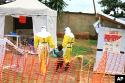 FILE - Health workers walk with a boy suspected of having been infected with the Ebola virus, at an Ebola treatment center in Beni, near Congo's border with Uganda, Sept. 9, 2018.
