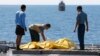 FILE - Crew members inspect bags containing bodies believed to be victims of AirAsia Flight 8501 on the deck of Indonesian Navy ship KRI Banda Aceh, on the Java Sea, Indonesia, Friday, Jan. 23, 2015.