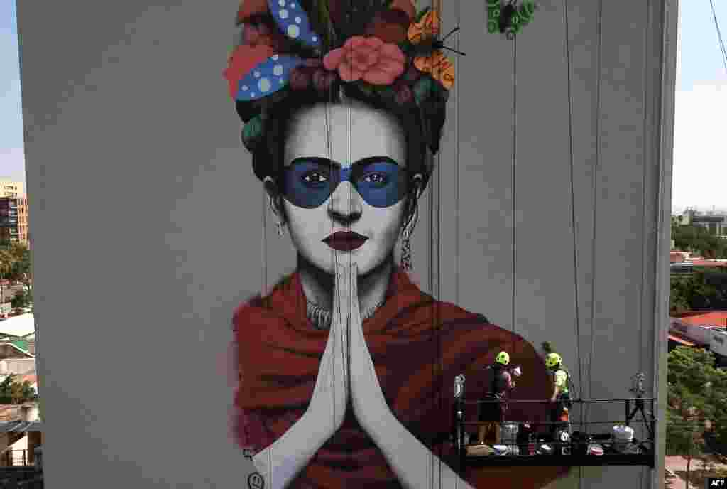 Irish urban artist Fin Dac (2-R) and his assistant work on his mural "Magdalena", in honor of Mexican painter Magdalena Carmen Frida Kahlo in the month of her birth, in Guadalajara, Jalisco state, July 9, 2019.