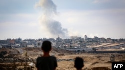 TOPSHOT - Watoto wakishuhudia moshi ukipaa angani wakati Israel ikifanya mashambulizi ya angani mashariki mwa Rafah eneo la kusini mwa Ukanda wa Gaza Mei 13, 2024, wakati vita kati ya Israel na Hamas vikiendelea. (Photo by AFP)