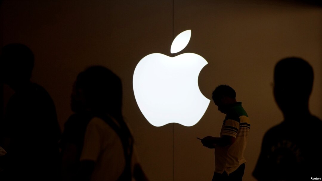 FILE PHOTO: A man looks at the screen of his mobile phone in front of an Apple logo outside its store in Shanghai