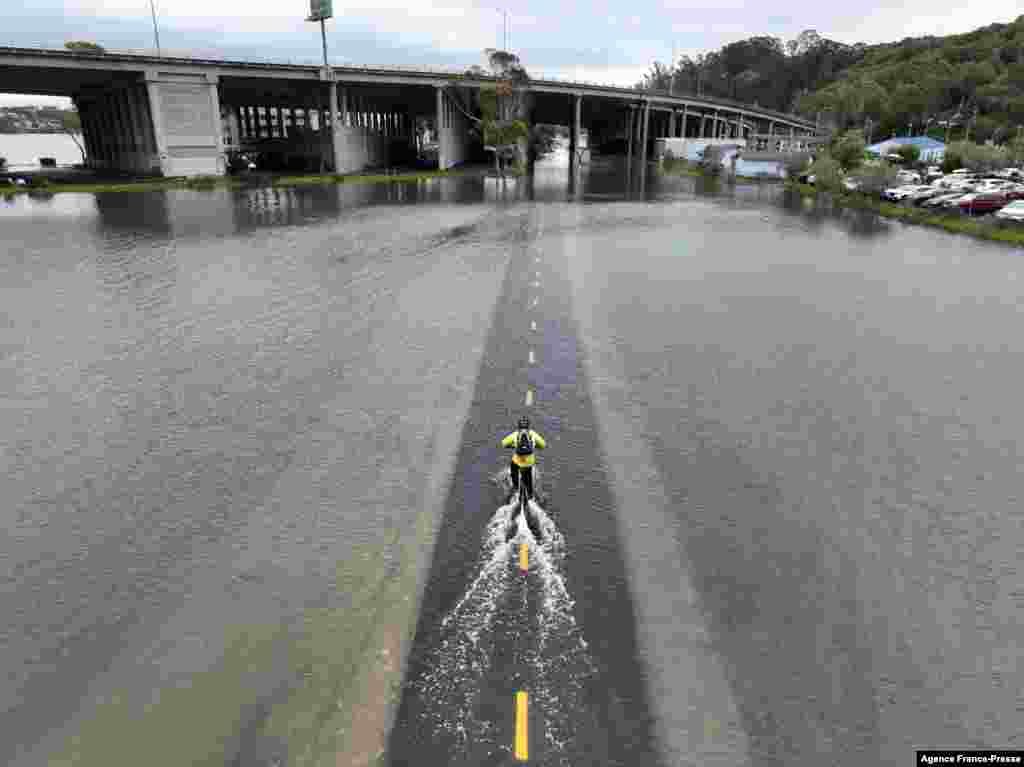 A man rides his bicycle along a flooded section of the Sausalito/Mill Valley bike path during the "King Tide" in Mill Valley, California, Jan. 3, 2022. "King Tides" occur when the Earth,the moon, and the sun align in orbit to produce unusually high water levels and can cause local tidal flooding.