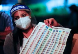 A polling station volunteer holds up a ballot during counting after polls closed in the municipal and parliamentary elections in San Salvador, El Salvador, February 28, 2021. REUTERS/Jose Cabezas