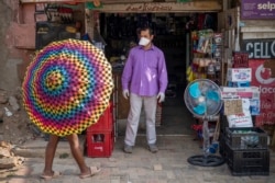 Iftikhar Ahmad, un comerciante pakistaní, es uno de los pocos que lleva una máscara en el municipio de Diepsloot, al norte de Johannesburgo, Sudáfrica.