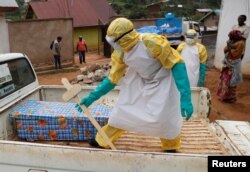 A health care worker carries a cross next to a coffin with a baby suspected of dying of Ebola in Beni, North Kivu Province of Democratic Republic of Congo, Dec. 13, 2018.