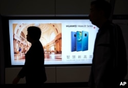 People walk past an advertisement for Huawei at a subway station in Hong Kong, Dec. 5, 2018. Canadian authorities said they have arrested Huawei's chief financial officer Meng Wanzhou.