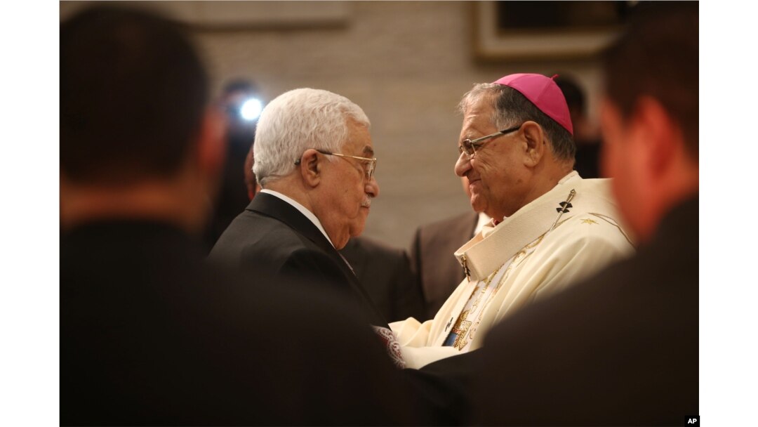 Palestinian President Mahmoud Abbas, left, greets the Latin Patriarch of Jerusalem Fouad Twal during a Christmas Midnight Mass at the Church of the Nativity in the West Bank town of Bethlehem, Dec. 25, 2015.