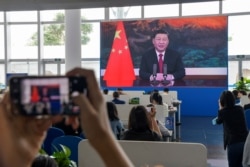採訪博鰲論壇的記者在媒體廳觀看屏幕上顯示的中國國家主席習近平在開幕式上講話的視頻。 （2021年4月20日）