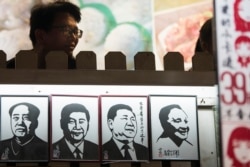 A man stands near a series of paper cuttings depicting Chinese President Xi Jinping next to former Chinese leader Mao Zedong and Deng Xiaoping. This photo was taken on March 1, 2018, in Shanghai.