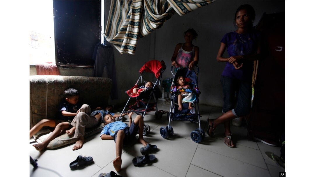 En esta foto del 27 de junio de 2018, algunas madres vigilan a niños venezolanos mientras otros trabajan, dentro de una casa escasamente amueblada compartida por unas 10 personas en Cúcuta, Colombia.