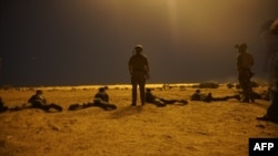 FILE - In this photo released by the U.S. Army on March 9, 2017, U.S. special operations forces observe as Nigerien service members fire their weapons with the assistance of illumination rounds during Exercise Flintlock 2017 in Diffa, Niger.