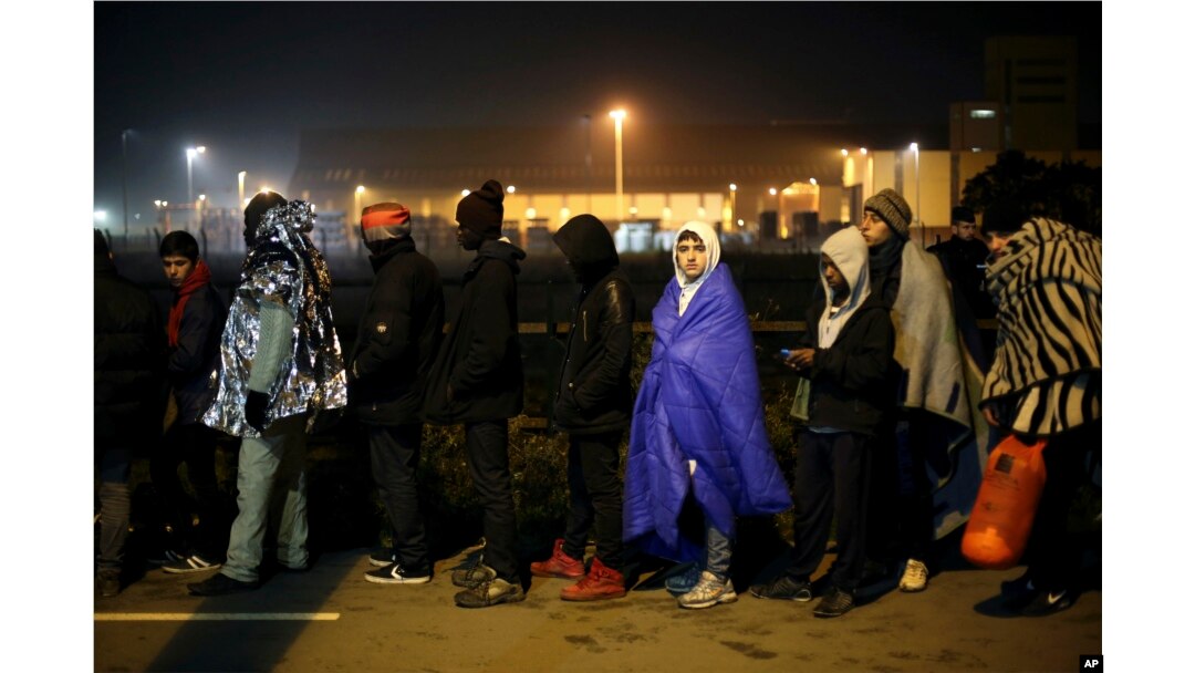FILE - Migrants wait to register outside a processing center in the makeshift migrant camp known as "the jungle" near Calais, northern France, Oct. 26, 2016.